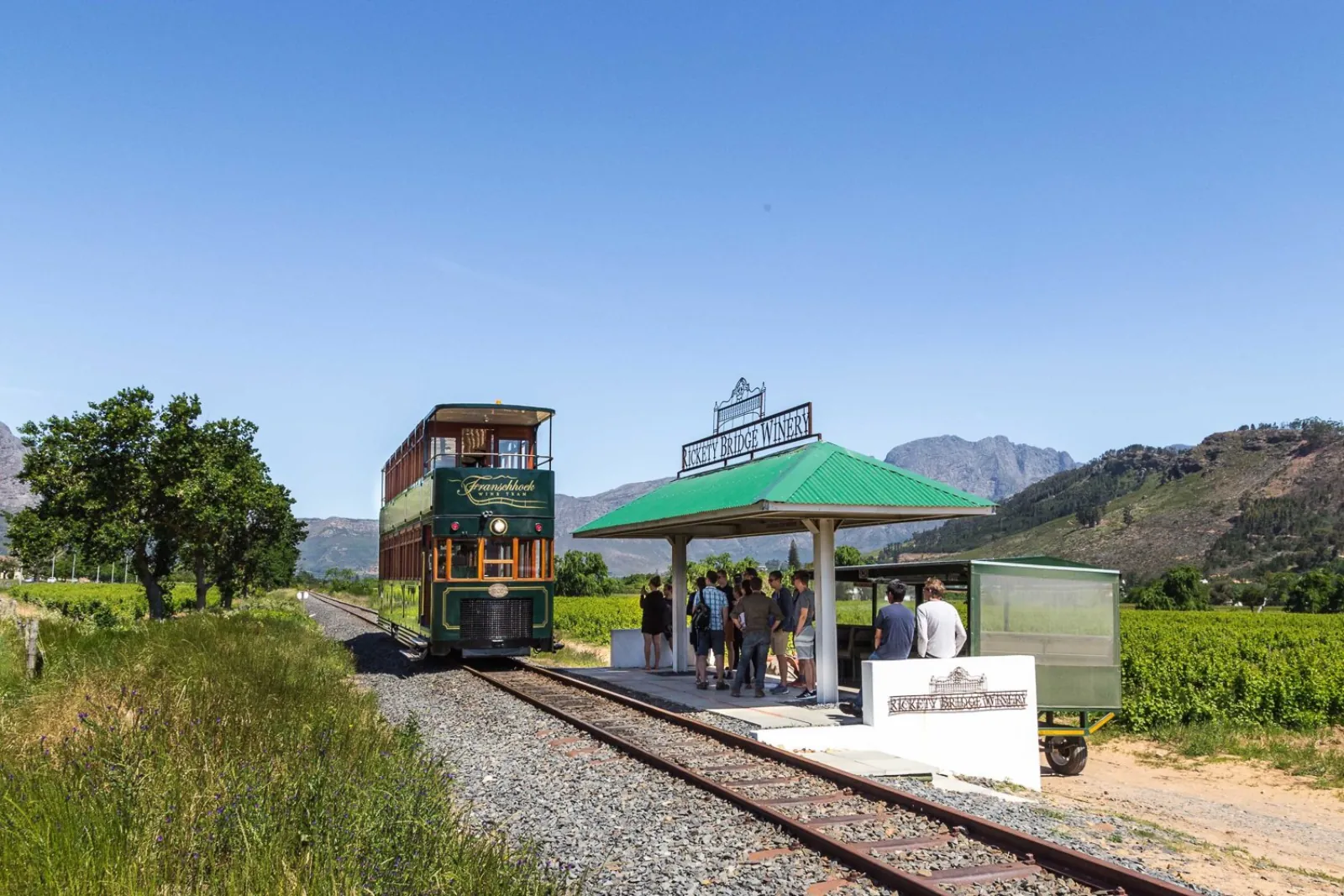 The Franschhoek Wine Tram waiting at an estate stop below the valley mountains