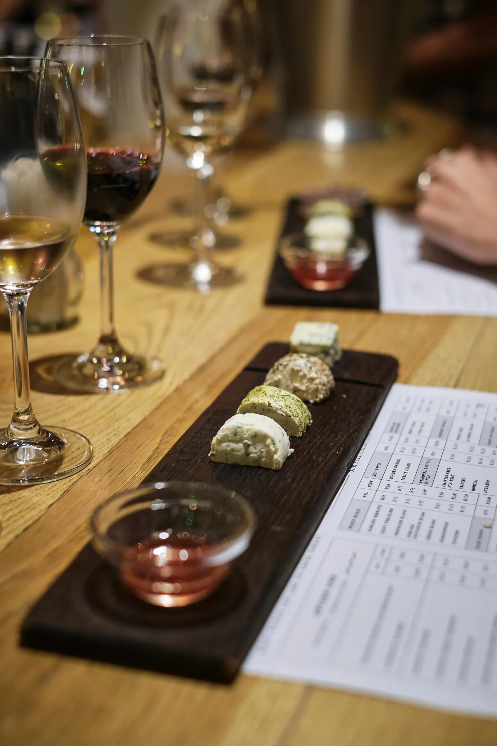 A wine tasting flight laid out on a wooden board with paired snacks