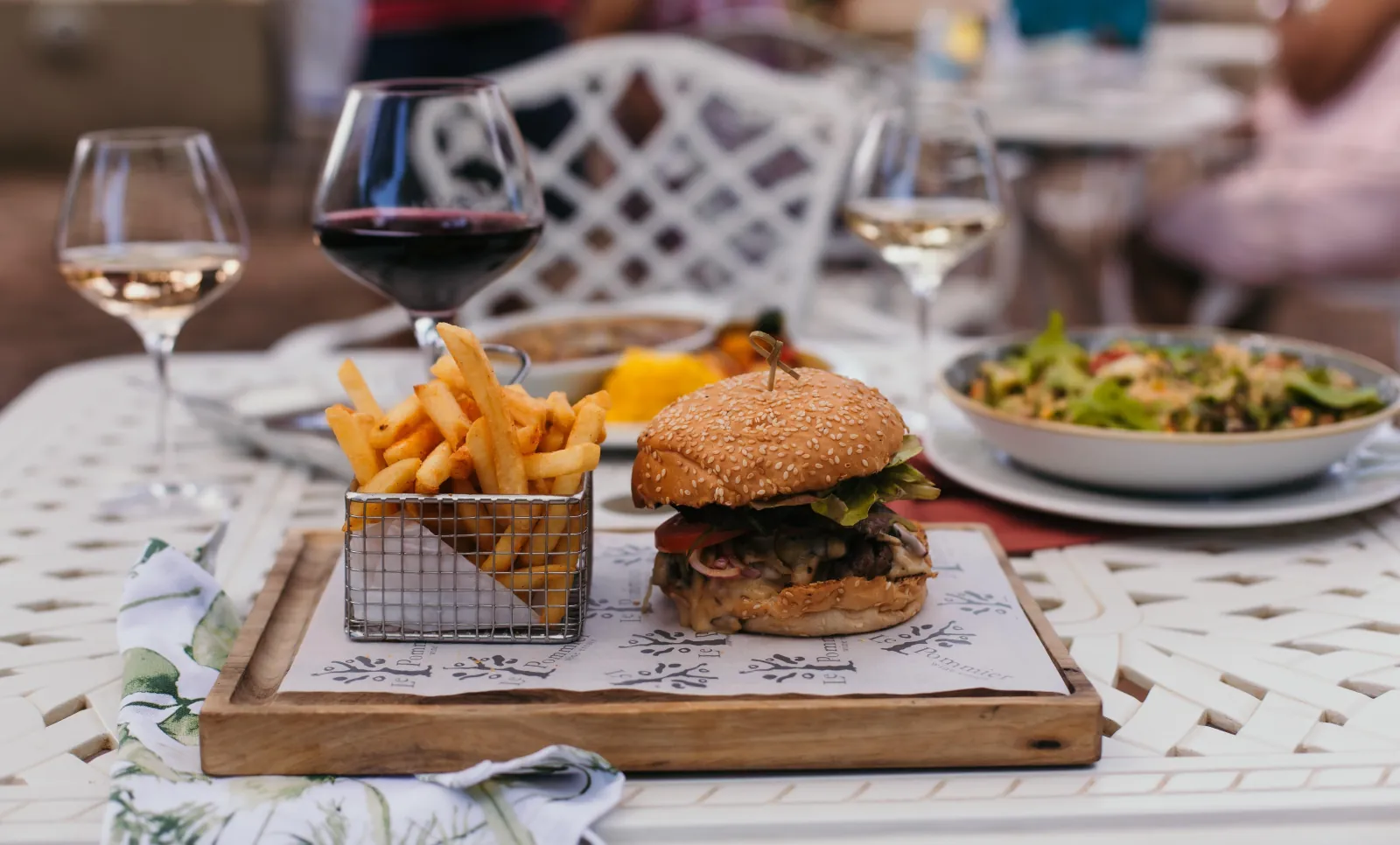 A vineyard lunch table set with red and white wine, a burger and a salad