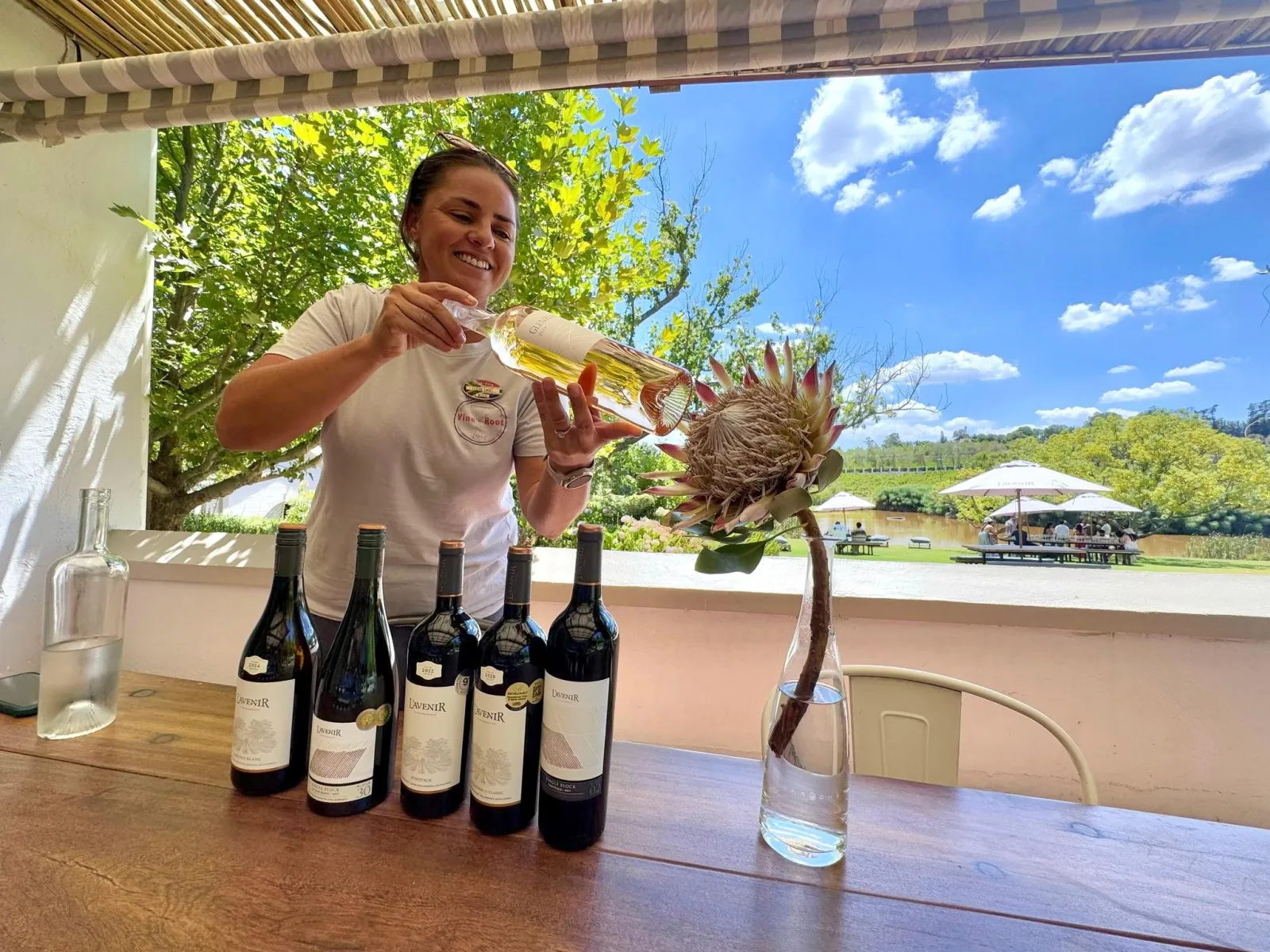 A host pouring a tasting at an open-sided estate tasting room